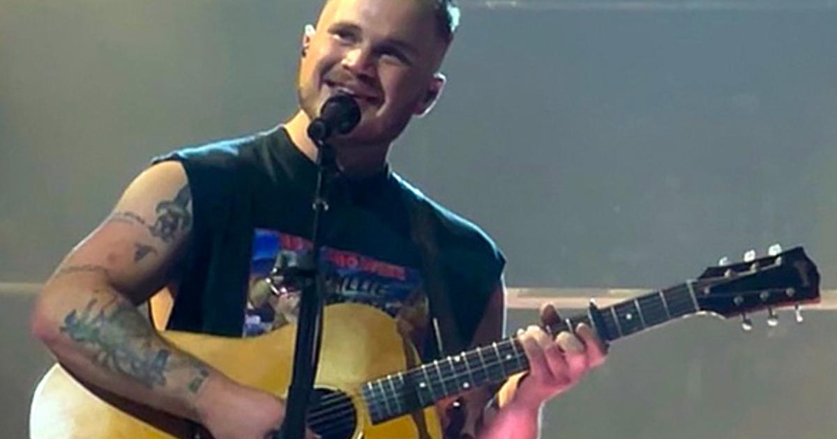 Zach Bryan performing on stage at arena concert